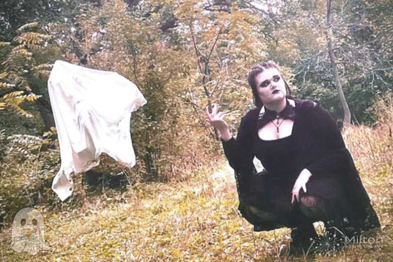 Gothic Girl Kneeling in Grass with Ghost Sheet in Tree