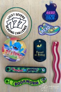 Colorful reading-themed tags and bookmarks are spread on a wooden table. Designs include