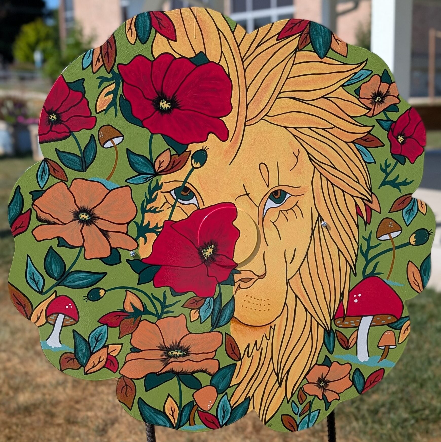 Poppy cut-out with a painting of a partically covered lion's face with colorful botanicals