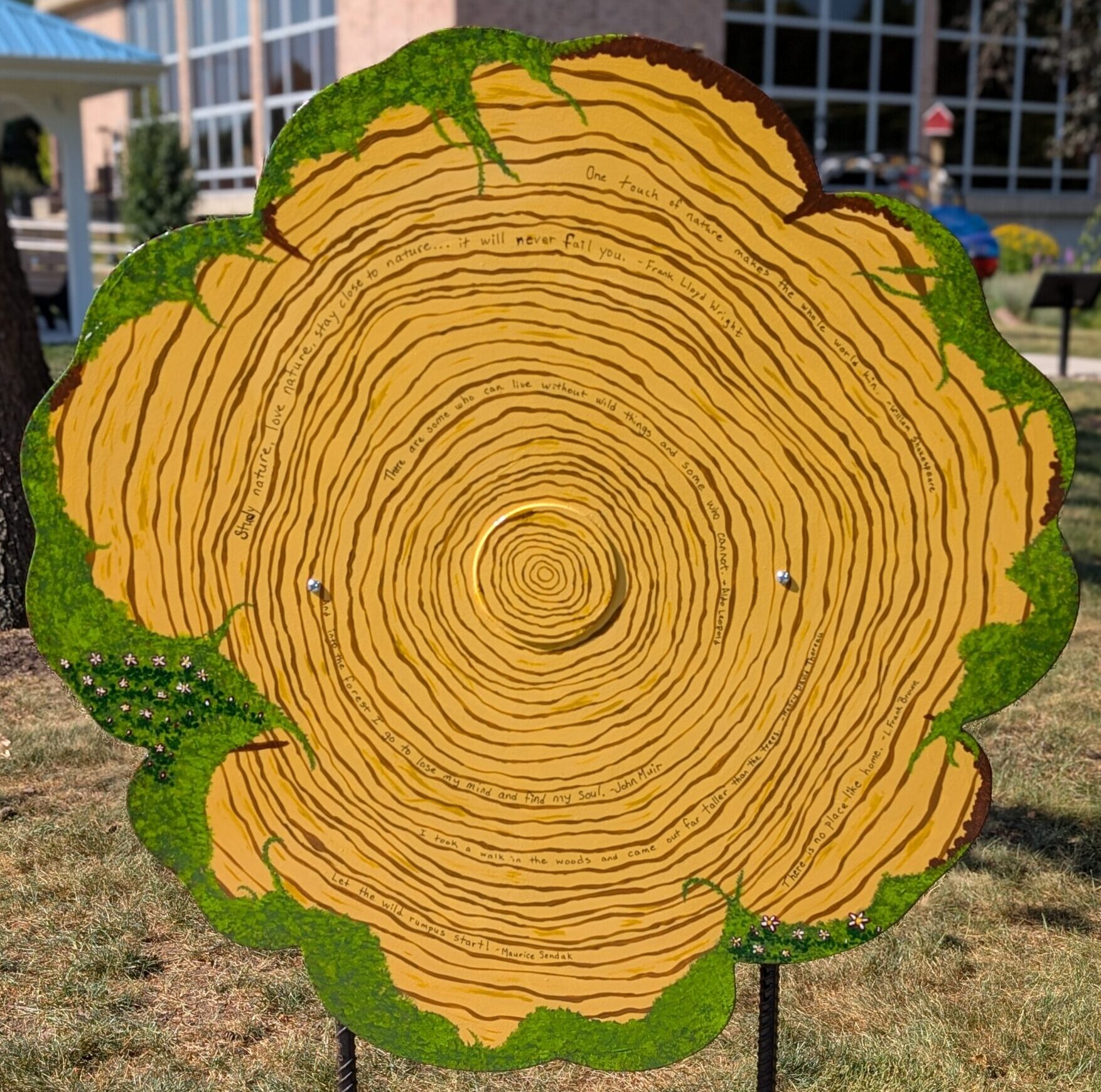 poppy cut-out painted to look like a cross section of a tree with tree rings, moss, and quotes
