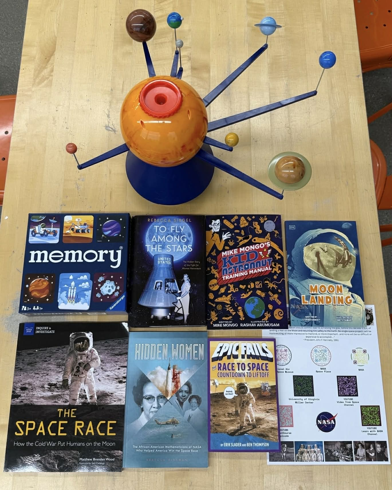 Collection of books, resources, and a model of the solar system on top of a table